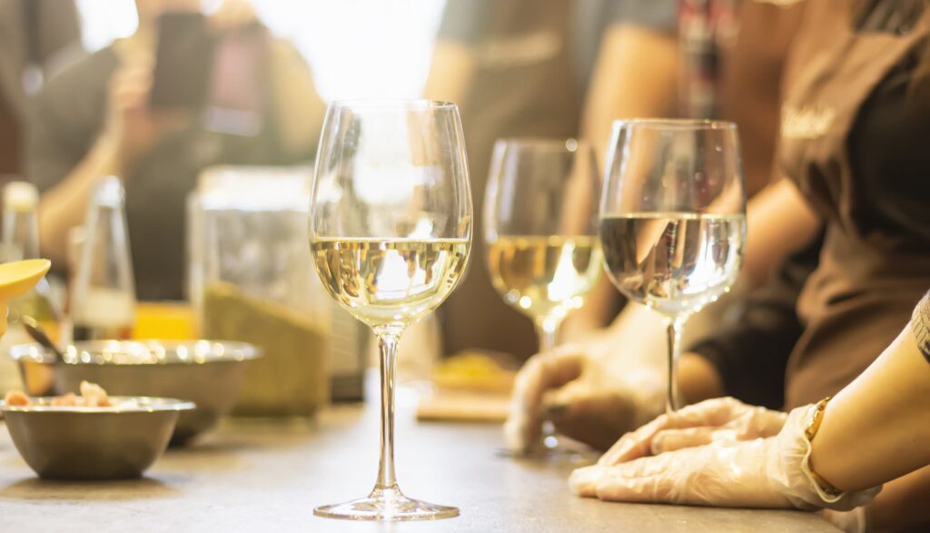 Riesling: Weingläser auf einem Tisch, Personen im Hintergrund
