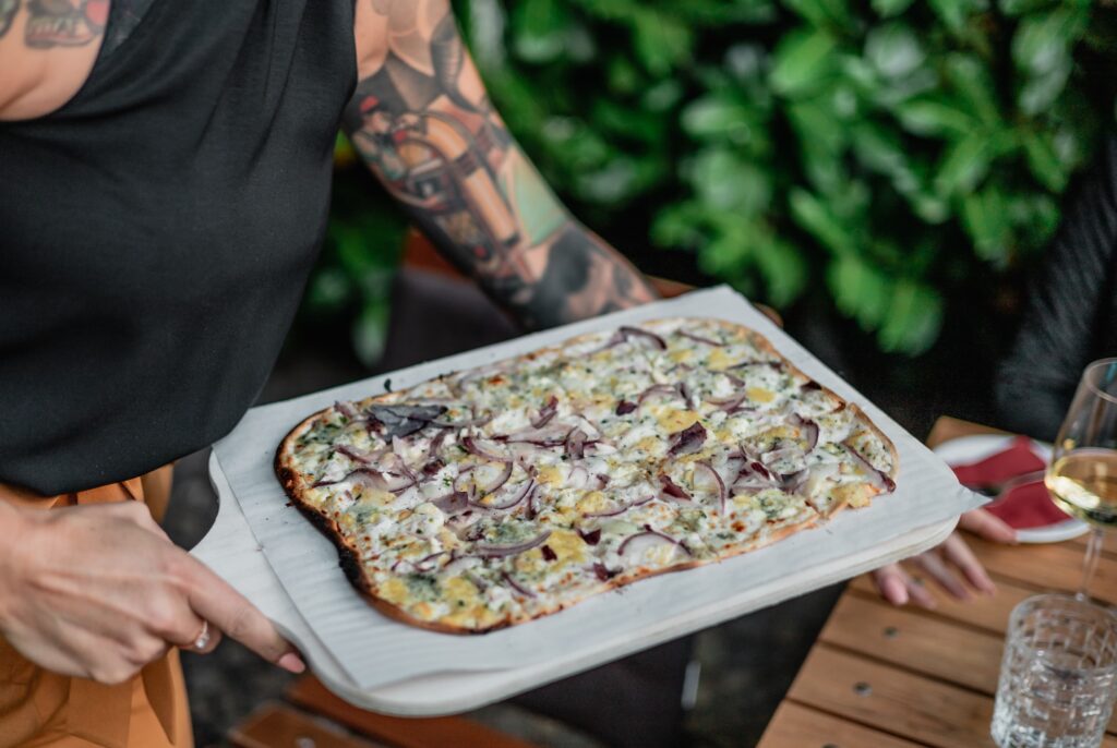 Eine Frau serviert Flammkuchen in der Barrel Winebar