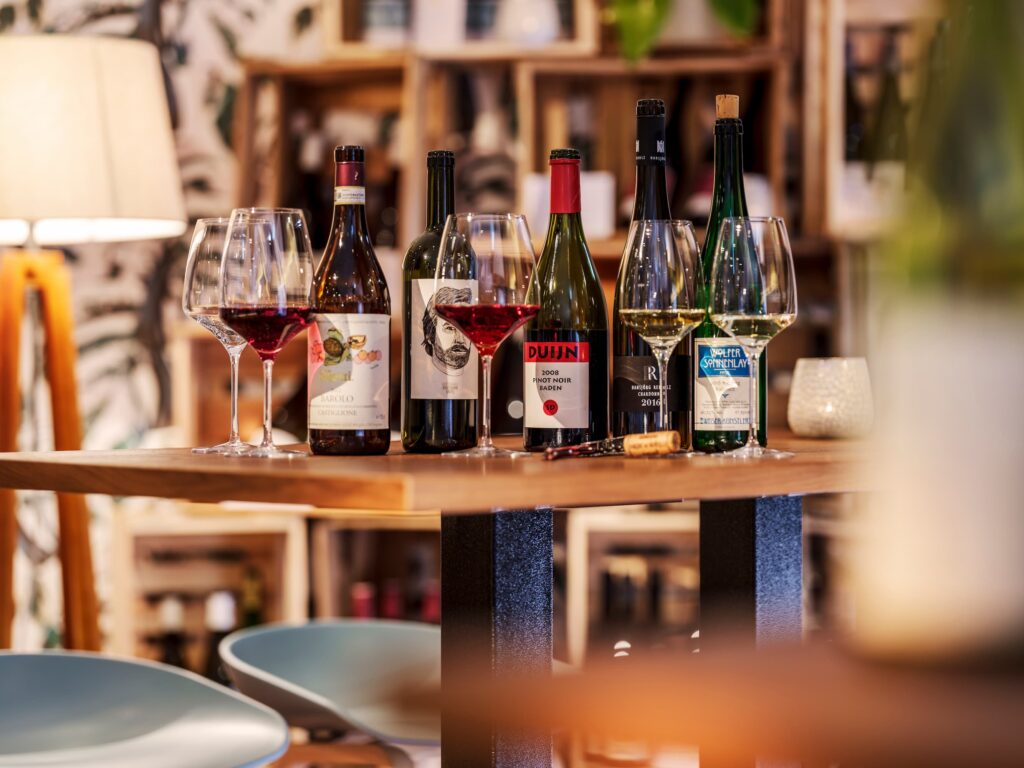 Ein Stehtisch, auf dem verschiedene Flaschen Wein und Gläser mit Wein darin stehen
