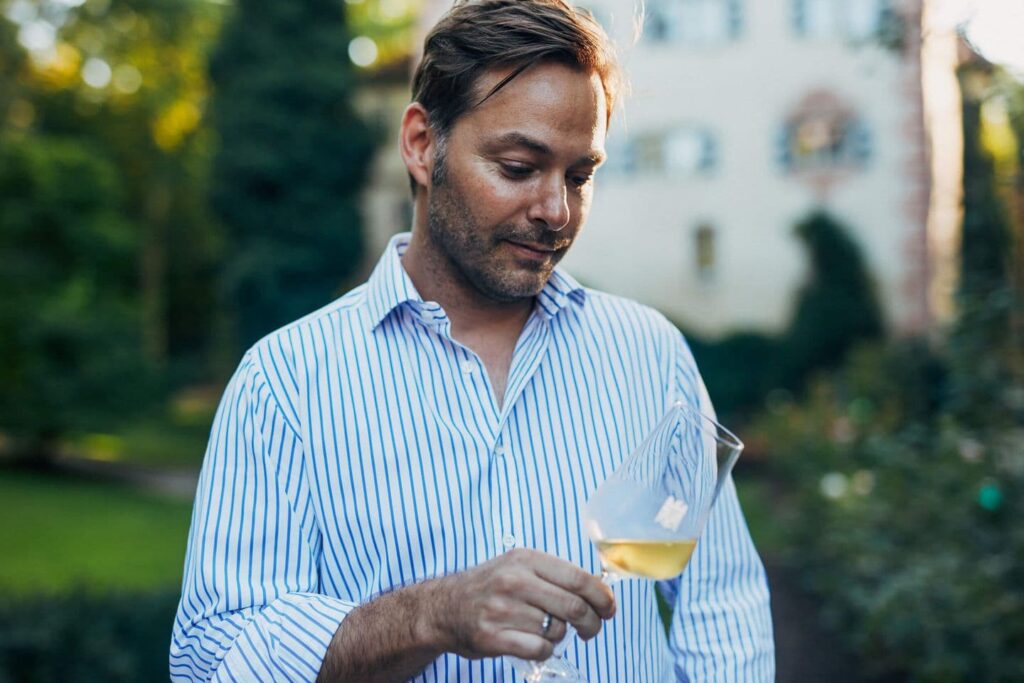 Felix Graf Adelmann mit einem Glas Weißwein in der Hand