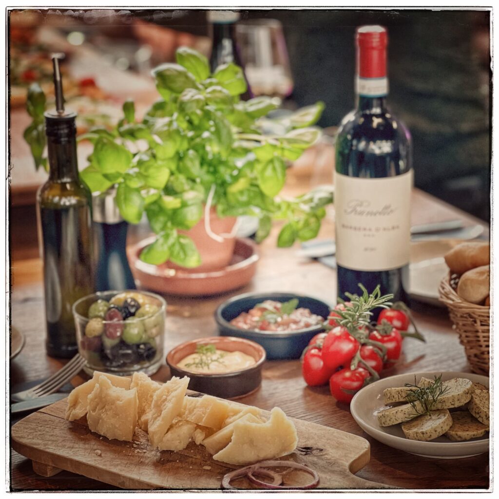 Verschiedene Antipasti auf einem Tisch, mittendrin eine Flasche Rotwein