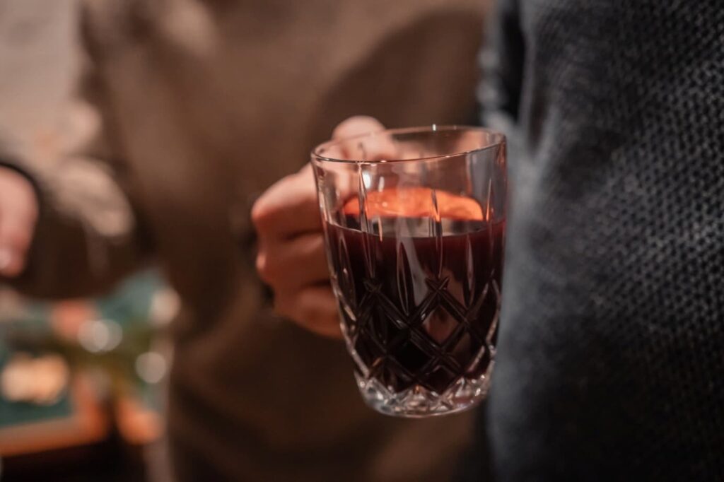 Eine Person hält eine Glastasse mit Glühwein in der Hand.