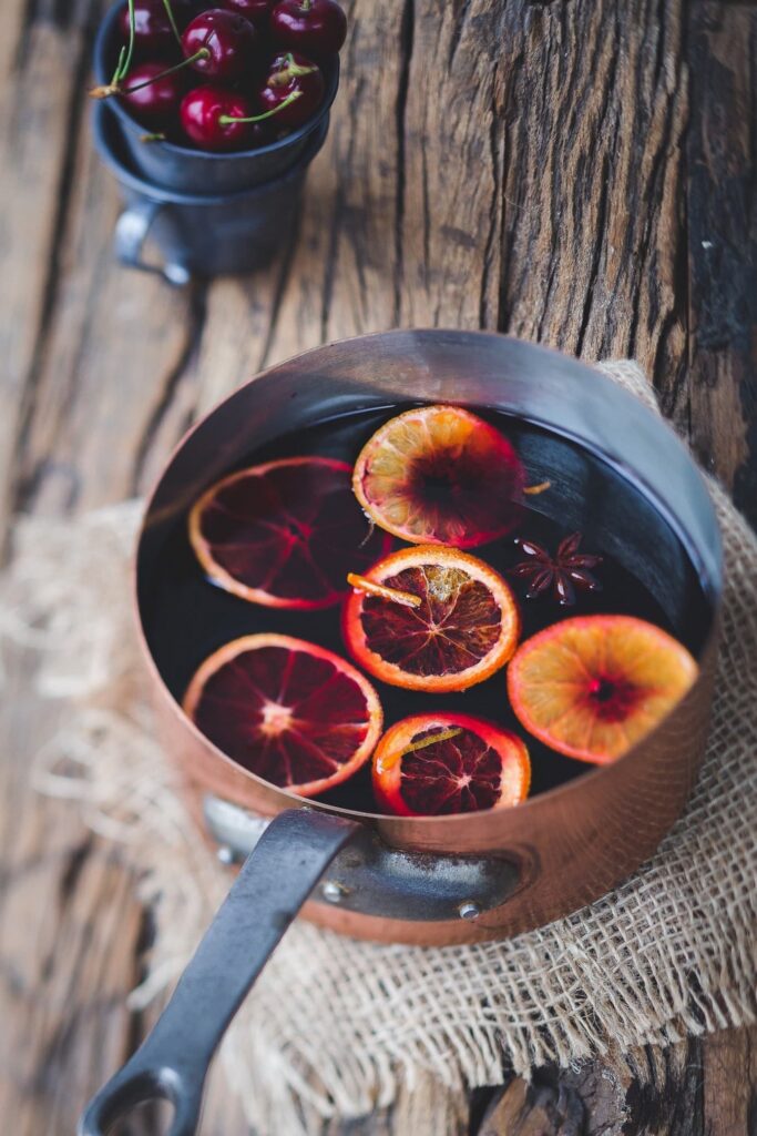 Ein Topf mit selbstgemachtem roten Glühwein mit Orangenscheiben, Zimt und Anis.