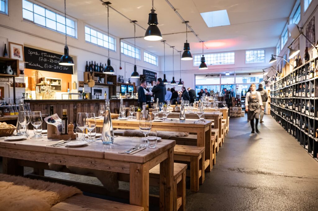 Vineyard Hamburg, Innenraum. Die Tische sind eingedeckt, im Hintergrund ein paar erste Gäste an der Bar