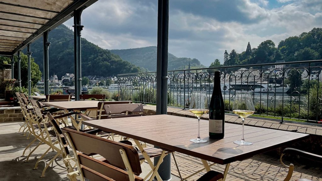 Terrasse der Bar Die Mosel, auf einem Tisch steht eine Flasche Wein und zwei Gläser